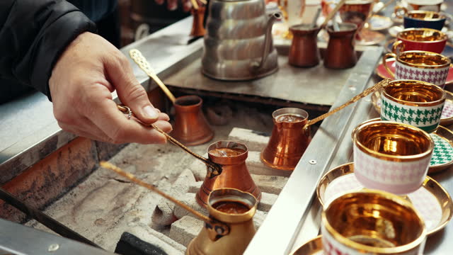 Preparing Turkish coffee in otantic 'cezve' pots and serving in cups with traditional ornamental designs
