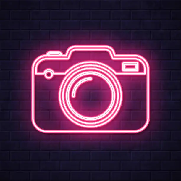 Vector illustration of Camera. Glowing neon icon on brick wall background