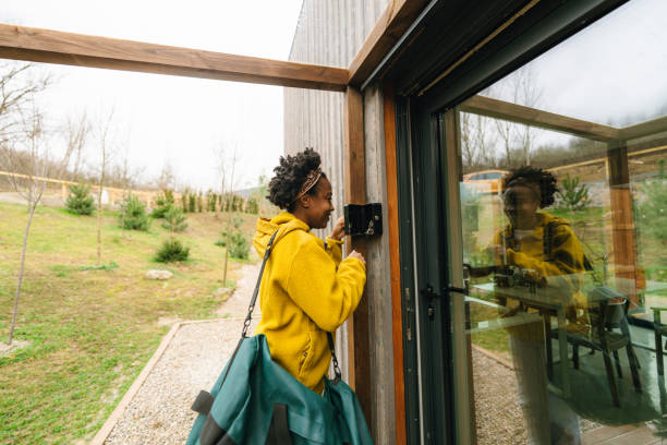 Young woman arrives at her vacation rental home Photo of young African American woman arriving at her vacation rental home and taking the keys out of a lock box key package stock pictures, royalty-free photos & images