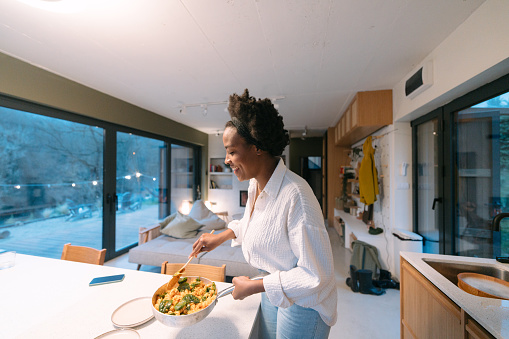 Photo of a young African American woman serving tastefully prepared dinner for herself in her dining room