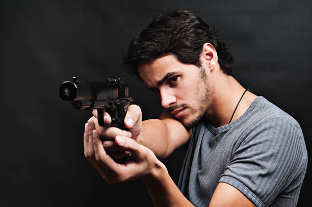 Casual young adult pointing with gun stock photo