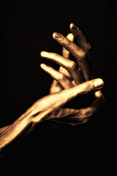 istock hands in golden paint on black background 176850282