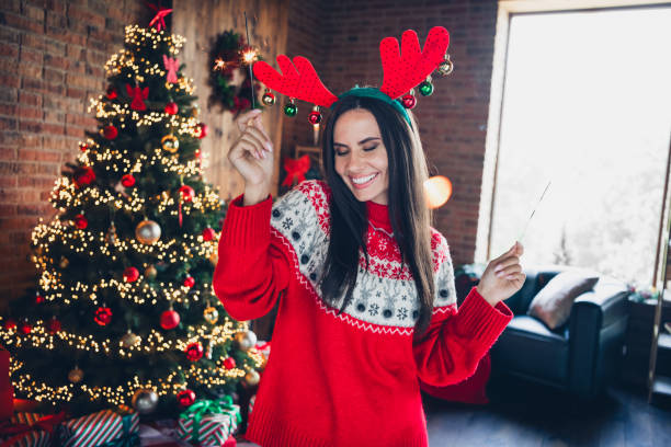 かなりブルネットの若い女の子の写真の肖像画は、ベンガルライトを保持し、踊りを楽しみます飾りのセーターを着て、美しいリビングルームの装飾、クリスマス - young animal flash ストックフォトと画像