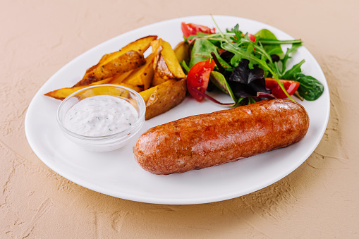 Roasted sausages with baked potatoes and green salad