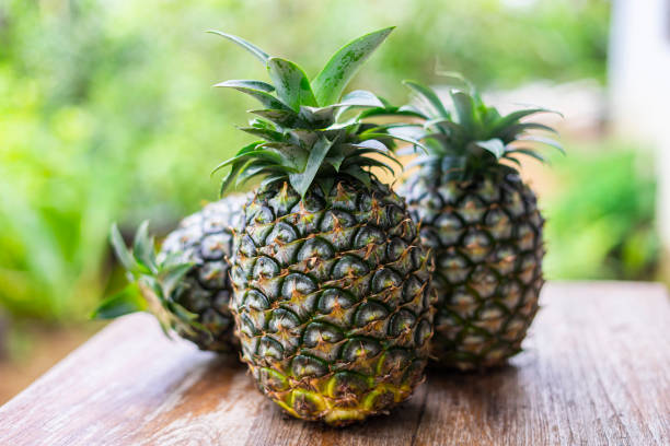 istock Whole pineapple on the wooden table with garden blackground. 1768520706