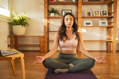 Woman sitting on her yoga mat and meditating
