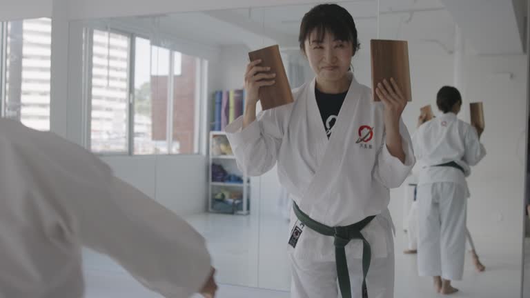 Japanese woman crushing wooden blocks in karate class