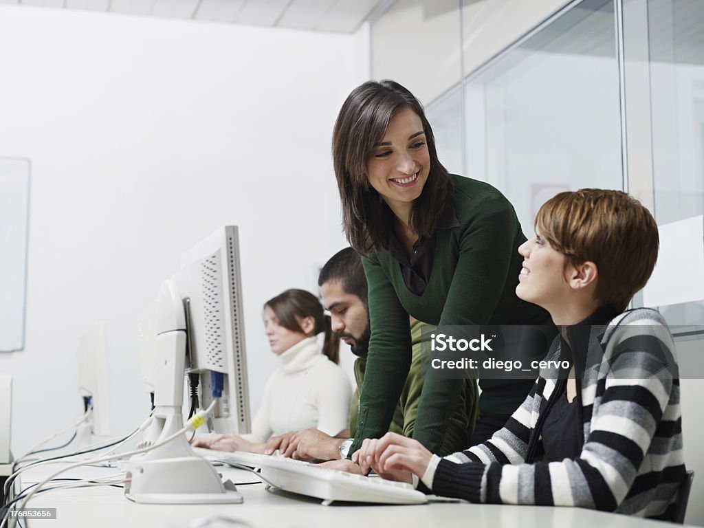 Teacher and students in computer class "Computer lab with caucasian female teacher helping student. Horizontal shape, side view, waist up, copy space" Computer Lab Stock Photo