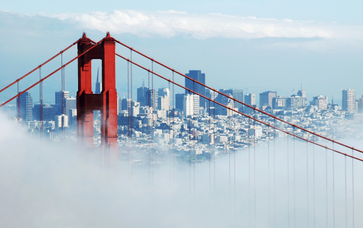 A shot of the famous Golden Gate Bridge and San Francisco from the Marin Headlands on a foggy day. The famous San Francisco landmark Transamerica Building is visible through the north tower of the bridge.