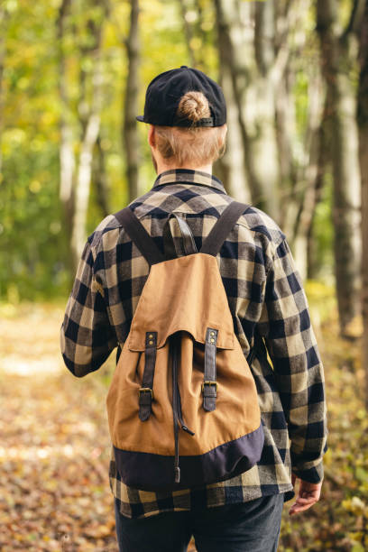 istock Traveler with a backpack is walking on an road along autumn forest. 1768548428