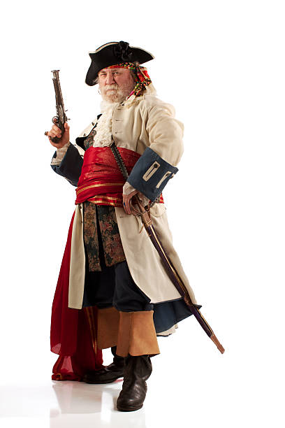 Classic bearded pirate captain in defiant pose "Traditionally costumed pirate captain with raised musket and wearing a sheathed sword. Full figure on white background, standing in a three quarter view.Click to see related images in my portfolio:" swashbuckler stock pictures, royalty-free photos & images