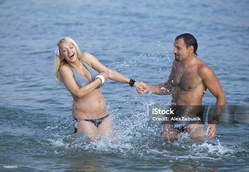 Attractive couple at the sea Middle aged man and young pregnant woman are playing in sea 40-44 Years Stock Photo