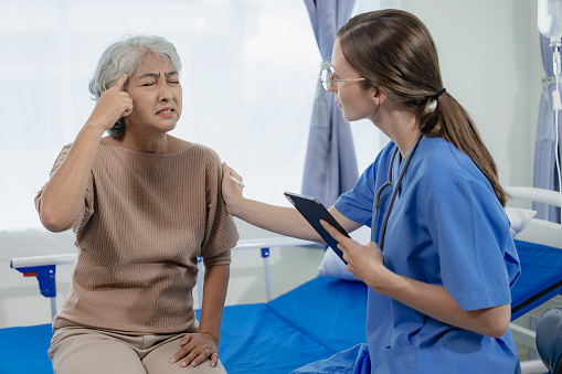 Female doctor with clipboard talking with elderly female patient at hospital Senior woman or doctor with digital tablet Consult or plan treatment to treat medical professionals with female patients.