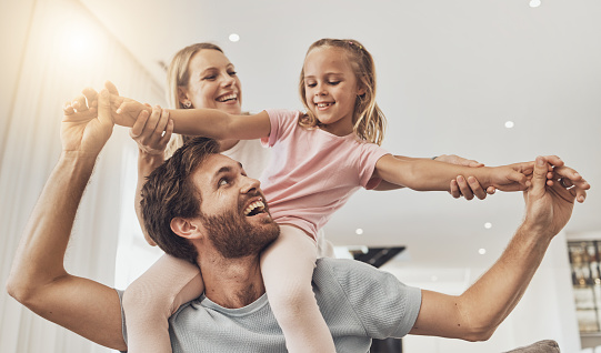 Home, playing and family with girl, parents and happiness with joy, fun and support on a weekend break. Child, mother and father with kid, support and relax with care, smile and cheerful in a lounge