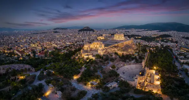 Aerial view of the illuminated skyline and ancient ruins at the Acropolis of Athens, Greece, with Parthenon Temple and Odeon of Herode theatre during evening