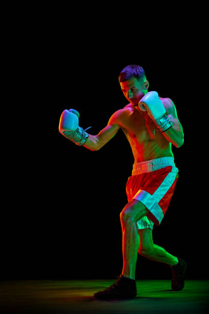 istock Professional male boxer, mixed martial art fighter training against over black mode background in mixed neon filter, light. 1768577905