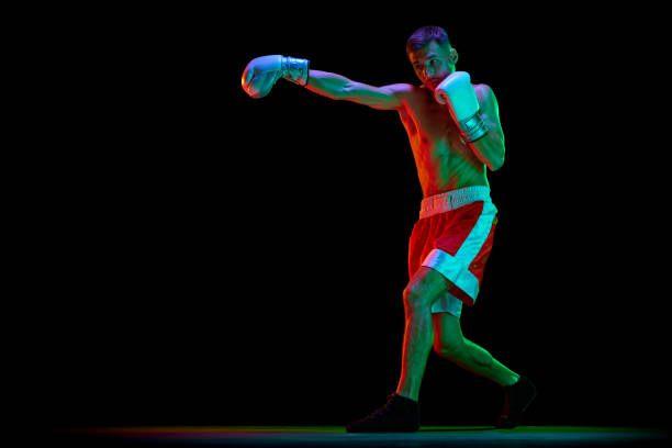 istock Professional male boxer, mixed martial art fighter training against black mode background in mixed neon filter, light. 1768577920