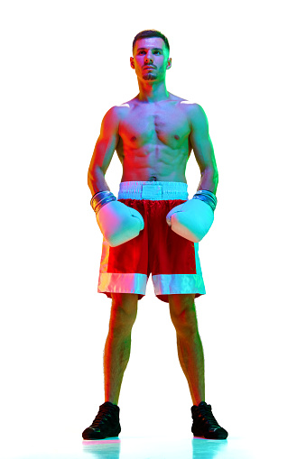 Full-length portrait of sportsman, boxer, mixed martial art fighter workout against white background in mixed neon filter, light. Concept of sport, action, motion, healthy lifestyle. Copy space for ad