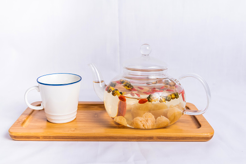 Longan, wolfberry and small yellow chrysanthemum tea served in cup and teapot isolated on wooden board side view of breakfast drink