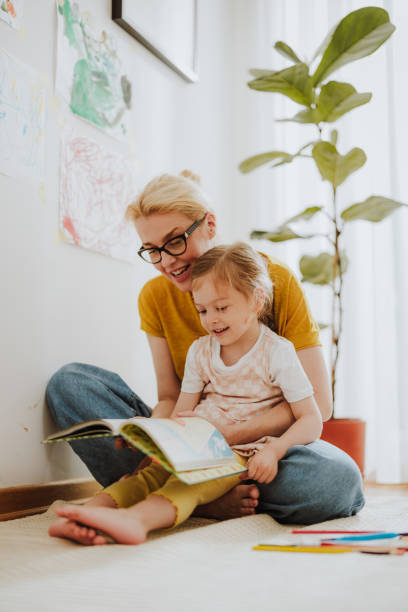 家で一緒に本を読む陽気な母と娘 - child reading mother book ストックフォトと画像