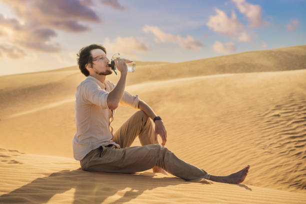 l’homme ressent la soif et boit l’eau dans le désert - thirsty desert men reaching photos et images de collection
