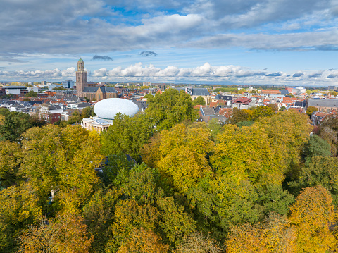 Zwolle downtown district aerial view during a a nice fall day. Seen from above we can see the luscioius fall foliage on the trees with various historical buildings in the background, such as the Peperbus church tower, Sassenpoort
