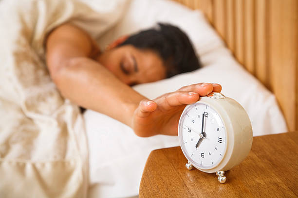 Woman waking up An Indian Asian woman wakes up and reaches to turn off a traditional alarm clockSimilar images from my portfolio: alarm clock snooze stock pictures, royalty-free photos & images