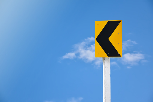 Left narrow curve traffic sign on pole with cloudy and bluesky background