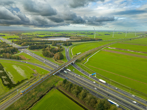 Traffic at a highway junction at Hattemerbroek where the N50/A50 and A28 highways cross on the border of Gelderland and Overijssel near Zwolle in The Netherlands. A train is driving over the railroad track in the foreground.