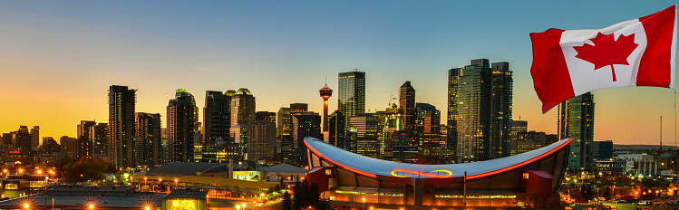 Canadian flag in front of view Calgary city skyline at twilight time, Alberta,Canada