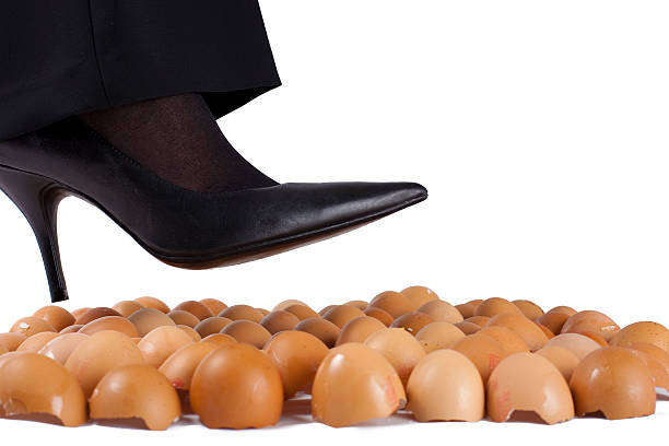 Walking on eggshells "Woman walking on egg shells in high heels, white background." animal egg walking on eggshells walking broken stock pictures, royalty-free photos & images