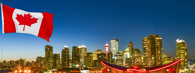 Canadian flag in front of view Calgary city skyline at twilight time, Alberta,Canada