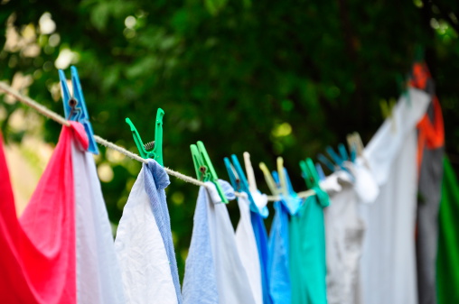 White clothes hung out to dry on a washing line in the bright warm sun. Background is a clear blue sky.