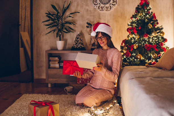 istock A young woman opens a Christmas present at home 1768602071