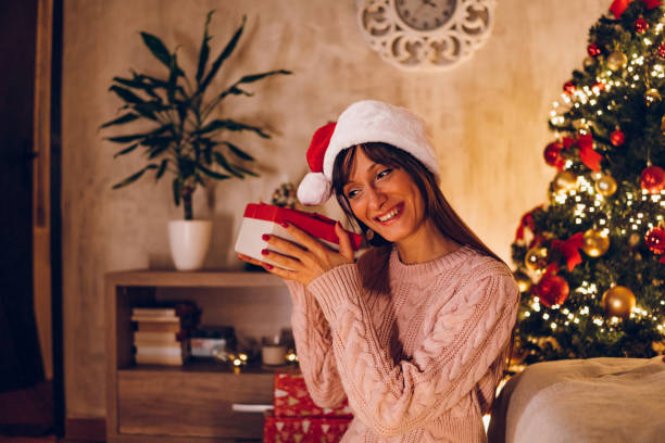 istock A young woman opens a Christmas present at home 1768602102