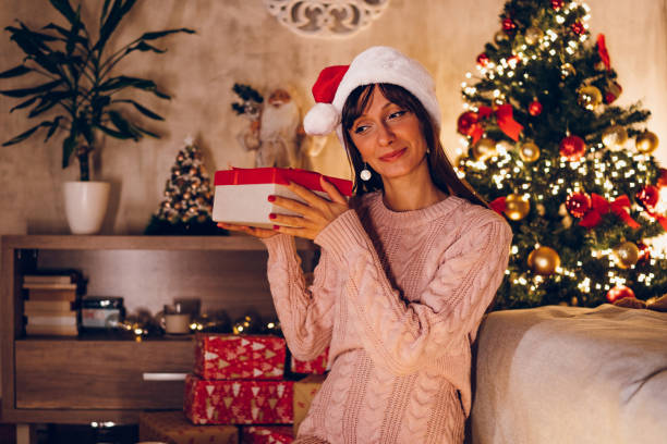 istock A young woman opens a Christmas present at home 1768604394