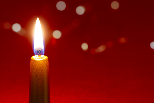 Red candle light Christmas candlelight on glowing flame sparkling red background blurred