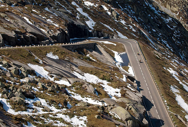 Winding Alpine mountain pass road turnpike mountain pass road on Grimsel pass in Switzerland in the European alps, with motorbike and bicycle traffic grimsel pass photos stock pictures, royalty-free photos & images
