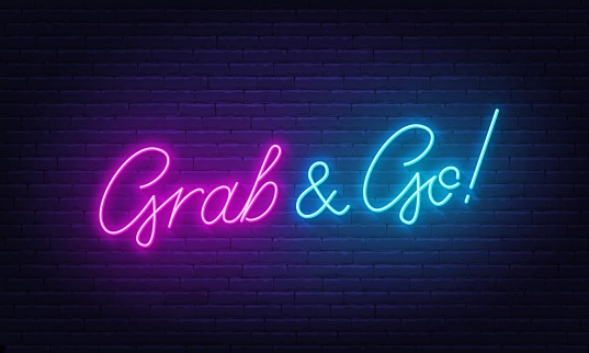 Grab and Go neon lettering on brick wall background.