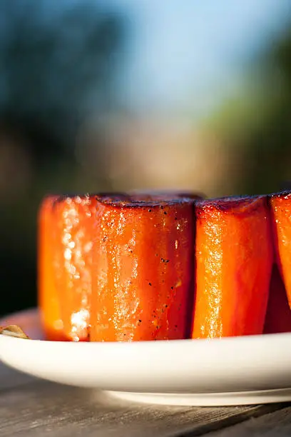 sticky stewed carrots as appetizer outdoors on wooden table