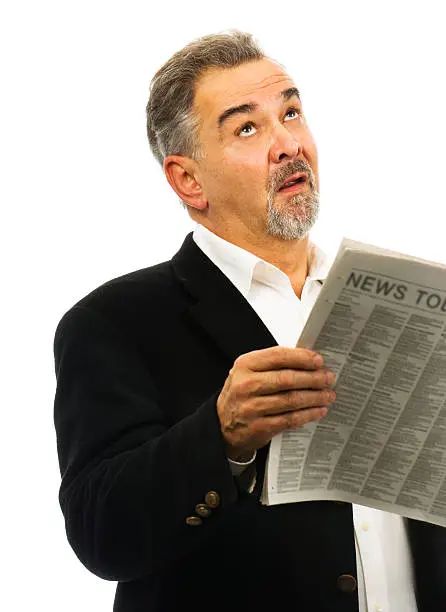 "Mature man, while holding his newspaper, looks skyward with a look of despair."