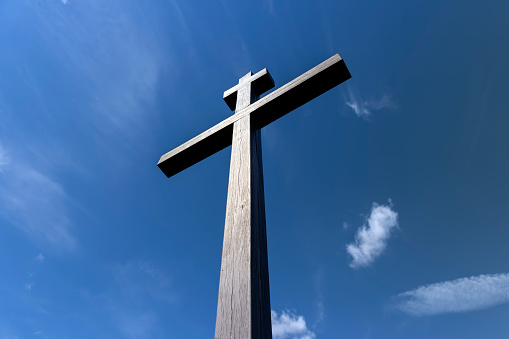 wooden christian cross on a blue sky background, wooden orthodox cross on a sky background with clouds