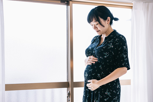 Young pregnant Japanese woman in her home