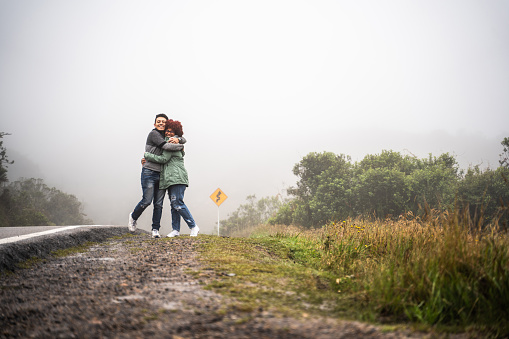 Young traveler couple embracing on the side of a road outdoors