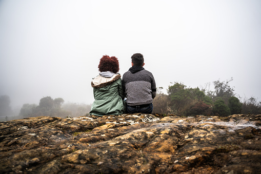 Rear view of a young couple sitting on a mountain peak in a Paramo, Colombia