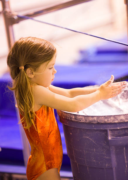 Little Gymnast Applying the Chalk A young girl gymnast applying chalk to her hands before a bar routine. Powdered talc helps the hands grip yet slide around the bars.  This image is filled with action: crisp focuse on eye, with slight motion blur in hands as the girl claps them together and talcum powder flies.   leotard stock pictures, royalty-free photos & images