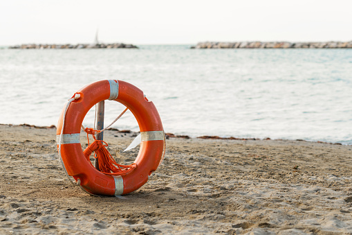 Orange lifesaver, life buoy or rescue buoy on sandy beach background