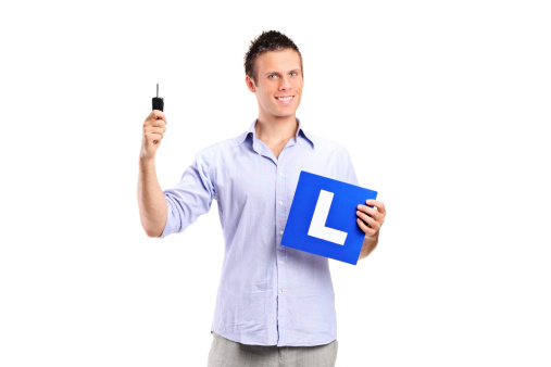 Happy man holding a car key and L plate isolated against white background