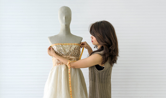 A skilled dressmaker taking precise measurements of a dress on a mannequin, exhibiting utmost care and detail.