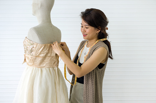 A skilled dressmaker fitting a dress on a mannequin, exhibiting utmost care and detail.